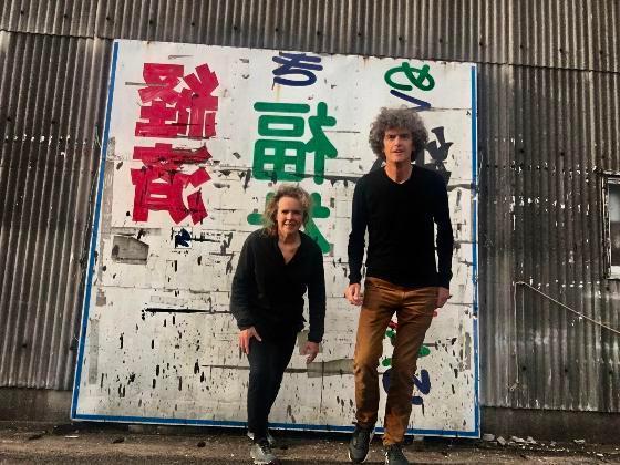 heringa and van kalsbeek in front of a large wall covered in artistic graffiti